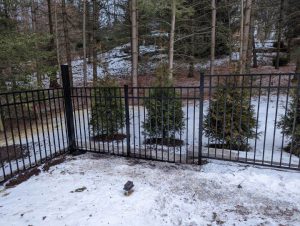 Photo of a black fence with snow on the ground