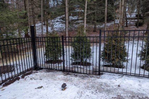 Photo of a black fence with snow on the ground